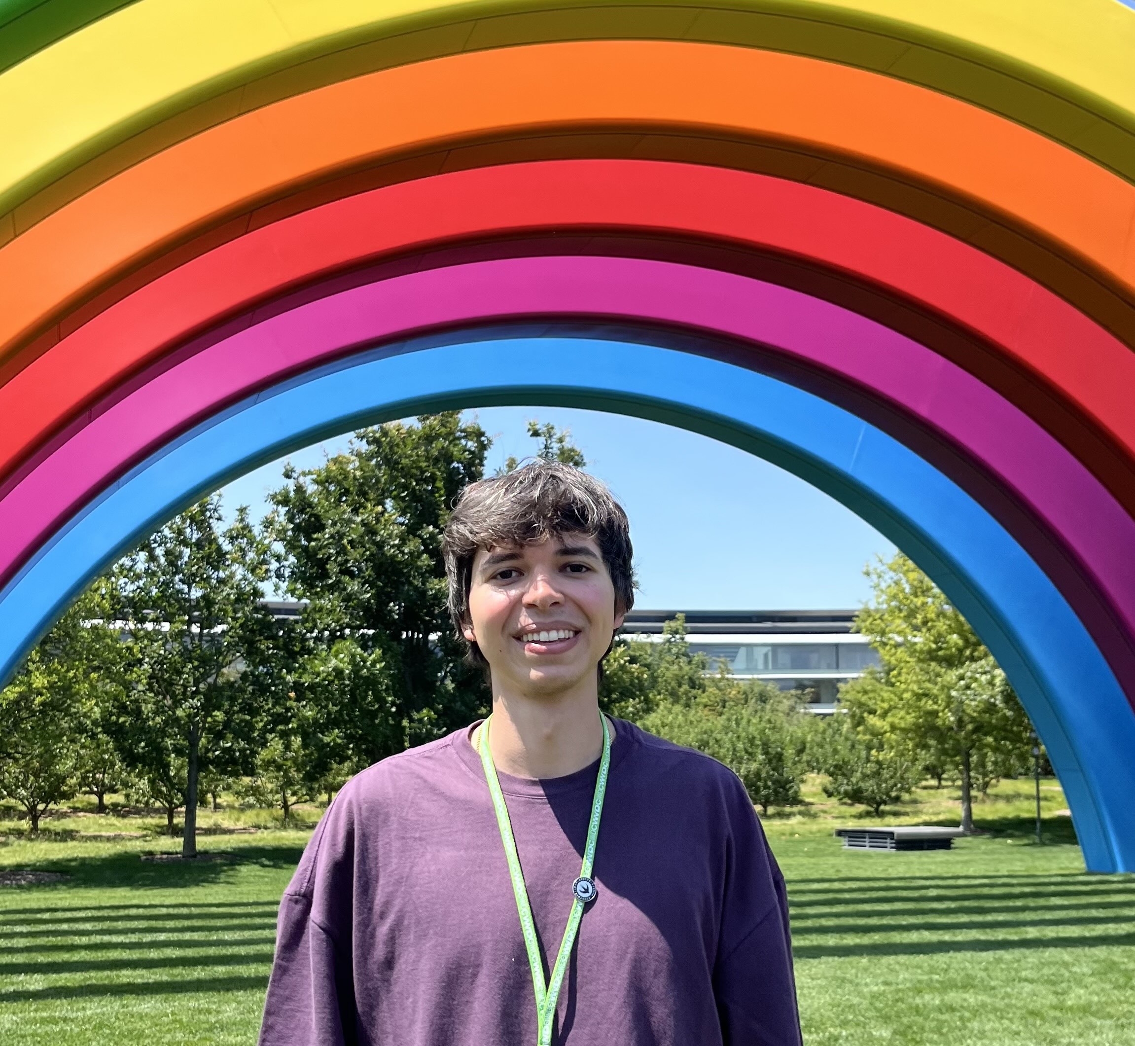 Thiago Parisotto smiling in front of the rainbow arch at Apple Park, Cupertino.
